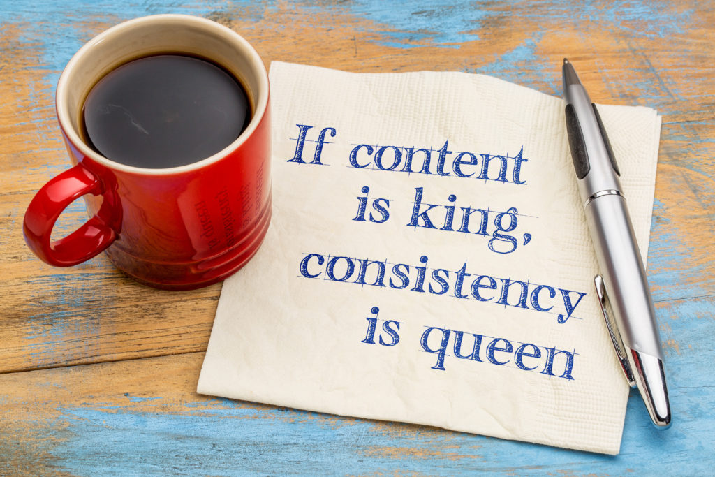 If content is king, consistency is queen - blogging and social media tip - handwriting on a napkin with a cup of coffee